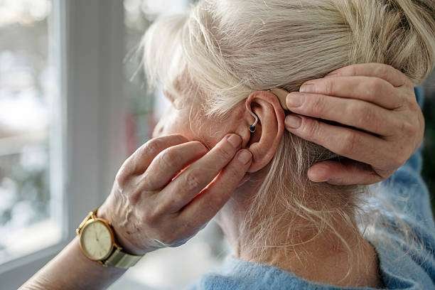 Senior woman applying hearing aid